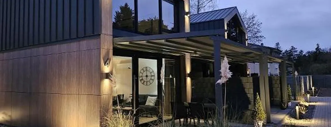 Gewerbebau mit Holzlamellenfassade und überdachtem Vorbereich in der Abenddämmerung